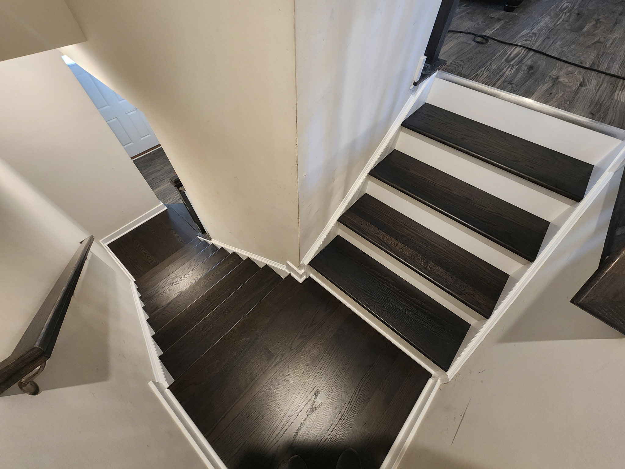 Top-down view of black-stained hardwood staircase with crisp white risers and landing