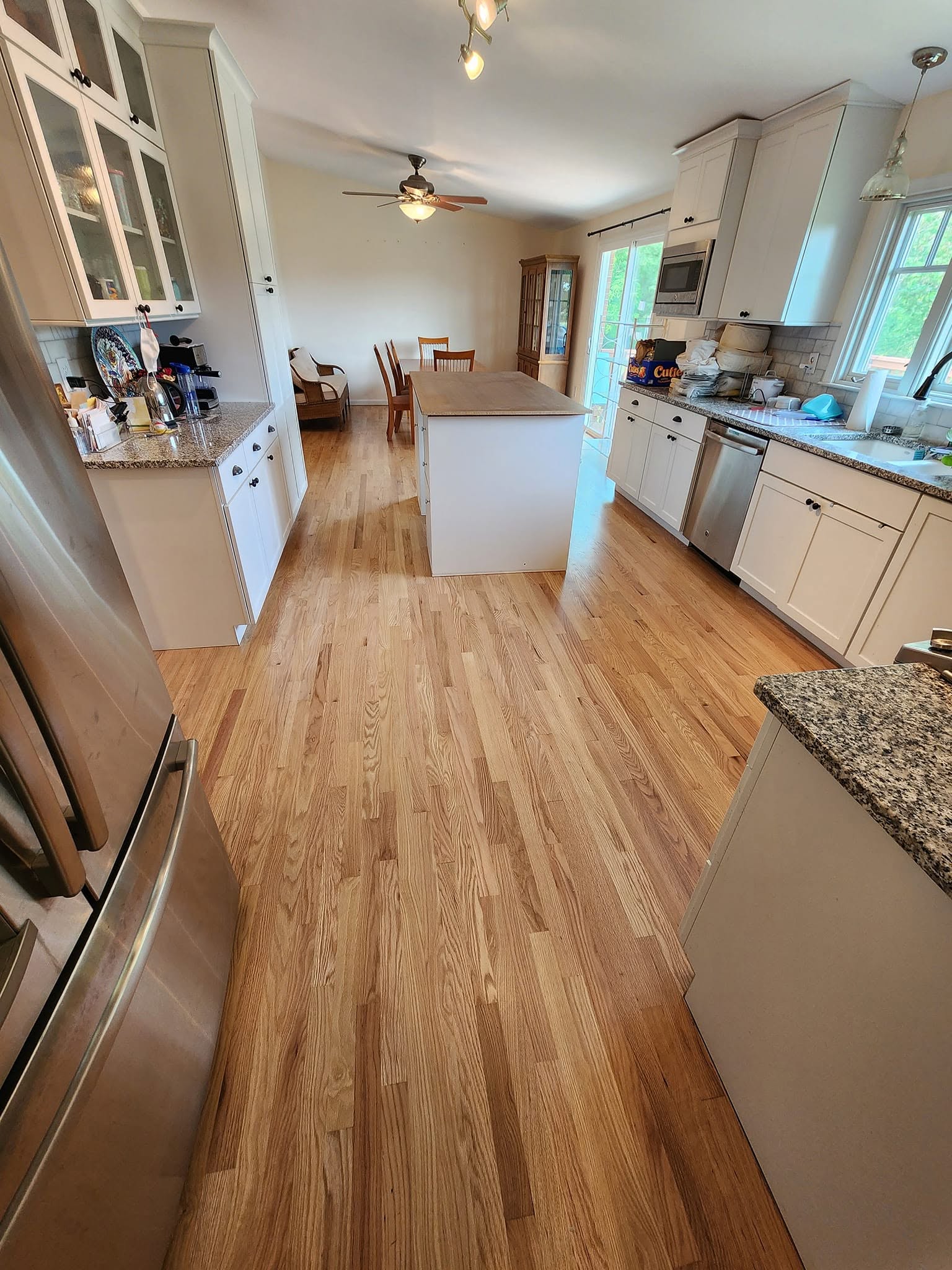 Finished hardwood floor in a living area near a fireplace and staircase