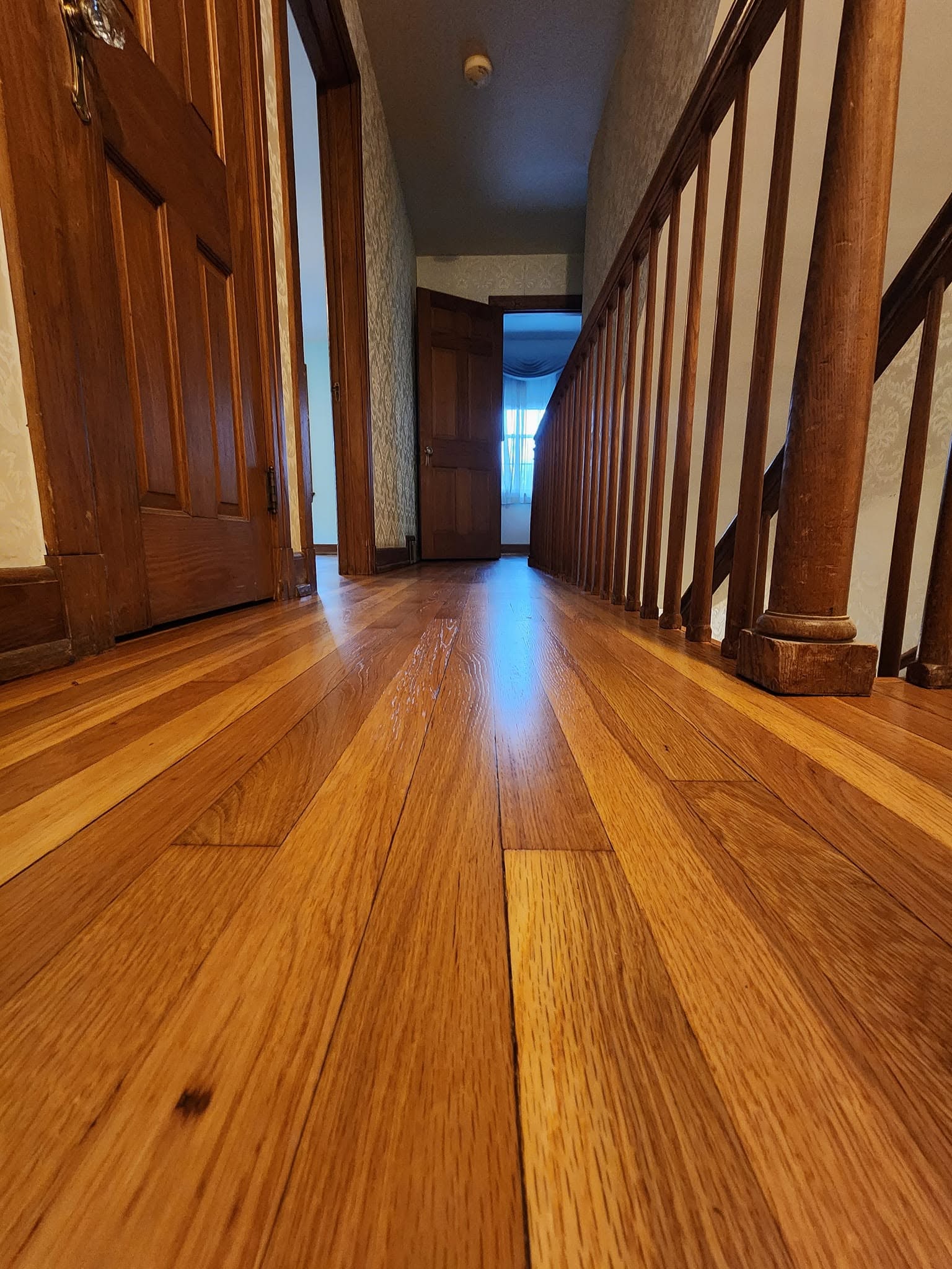 Wide finished hardwood room with a smooth satin finish and clean open layout